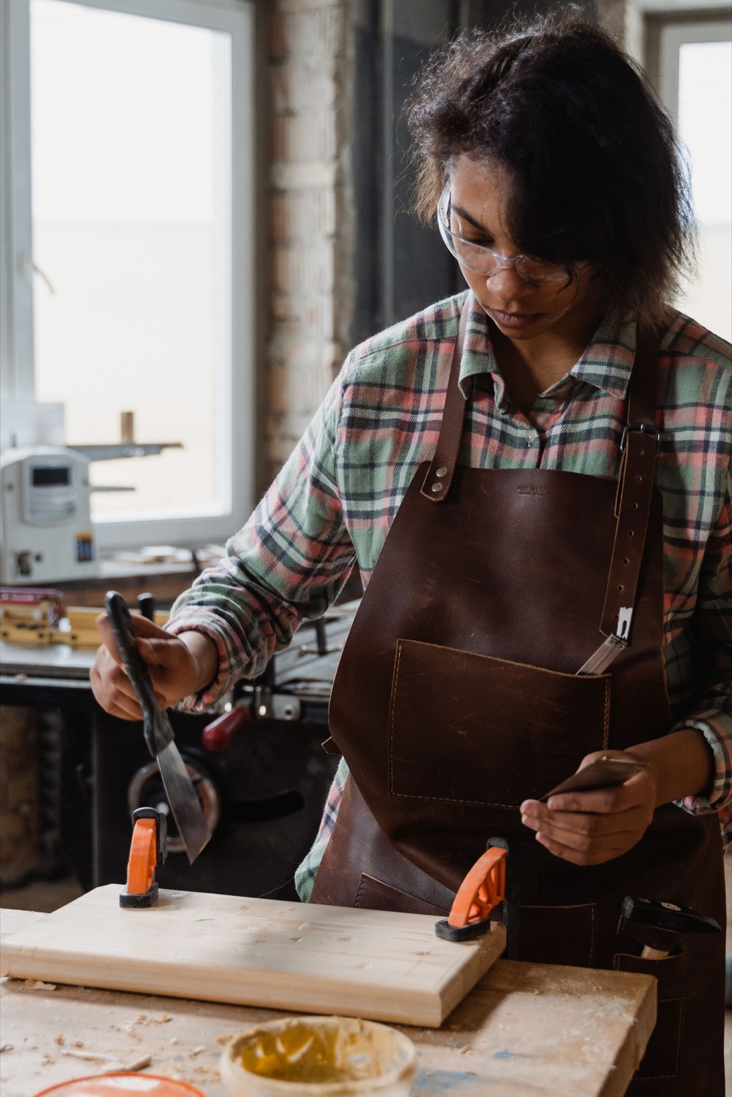 Woman carpenter in a workshop shaping a wood board at a workbench